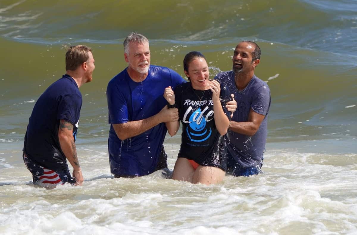 Pastors baptizing a young woman in the ocean at Neptune Beach