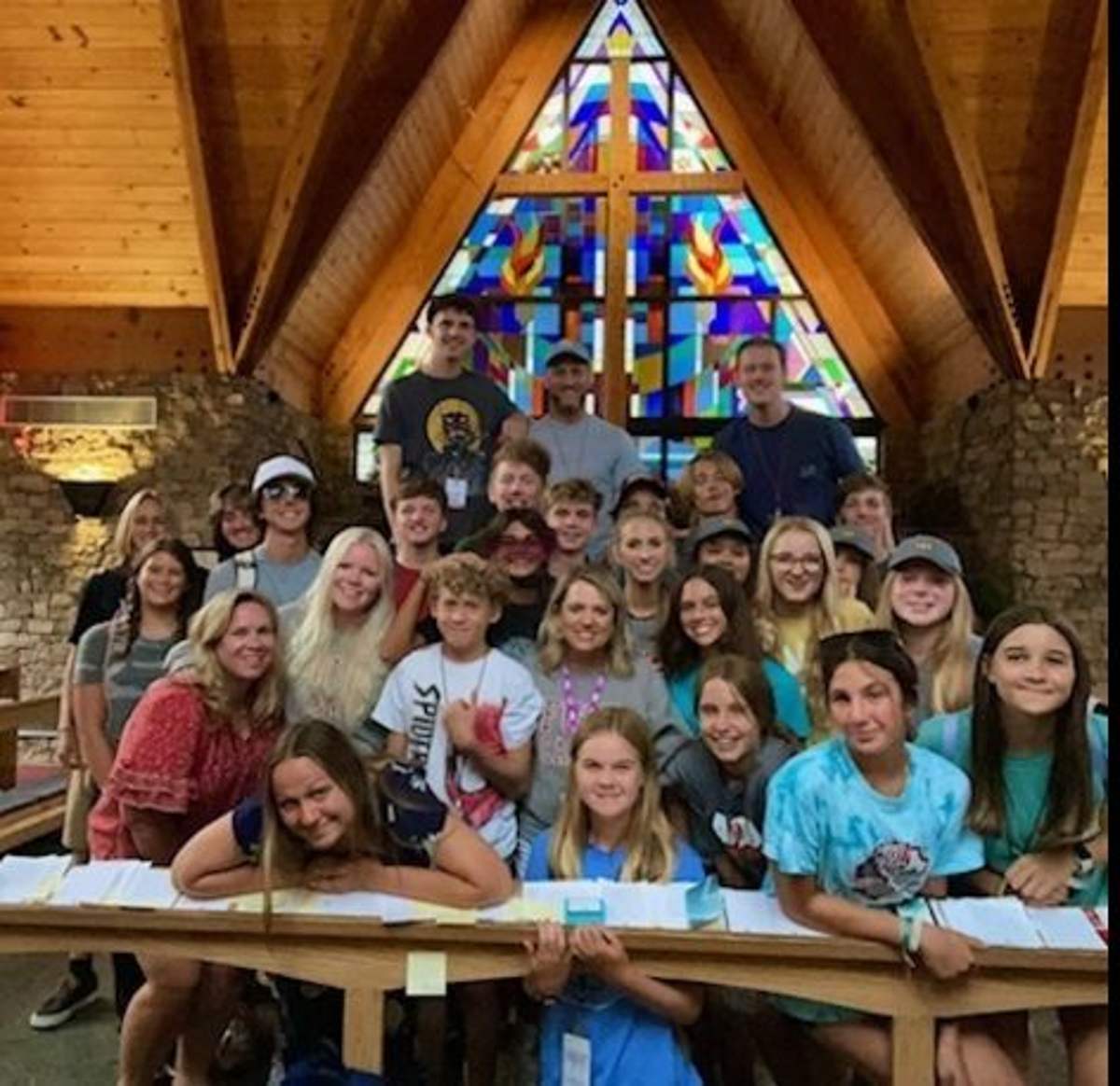 Students gathered in the sanctuary under the stained-glass cross